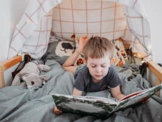 Junge liest im Kinderbett mit Höhle