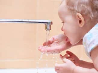 Kind trinkt Wasser aus dem Wasserkran