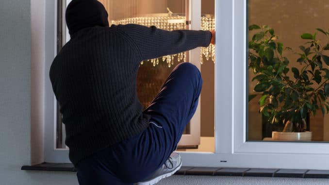 Einbrecher steigt durch ein Fenster ein